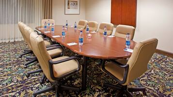 A conference room with a long table, multiple chairs, water bottles, and a patterned carpet.