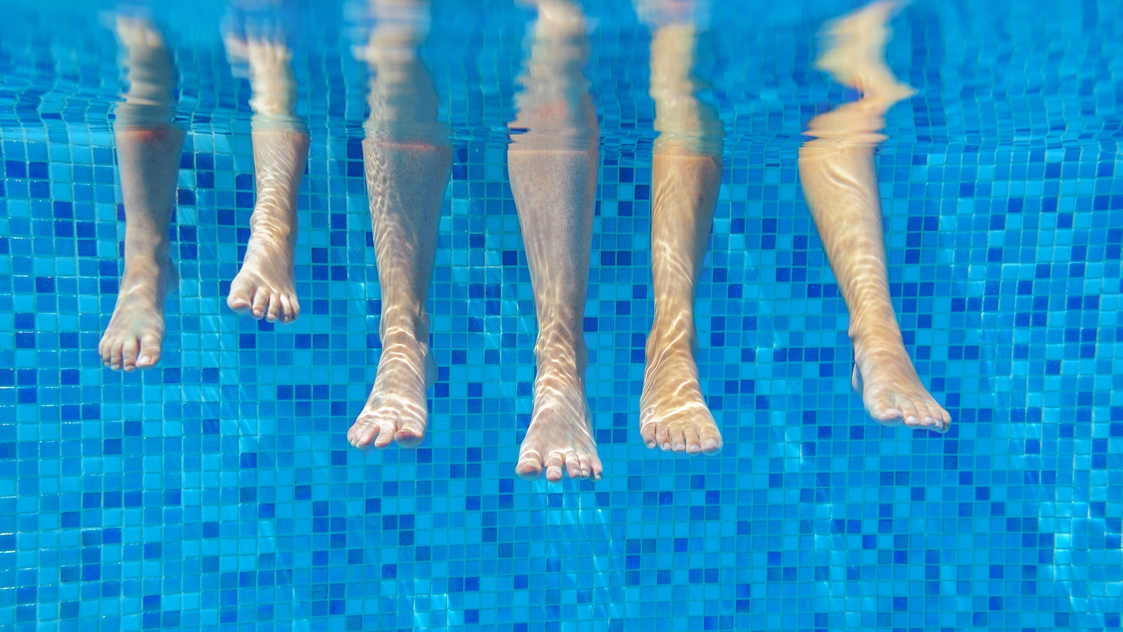 A pool with clear blue water and a tiled floor.