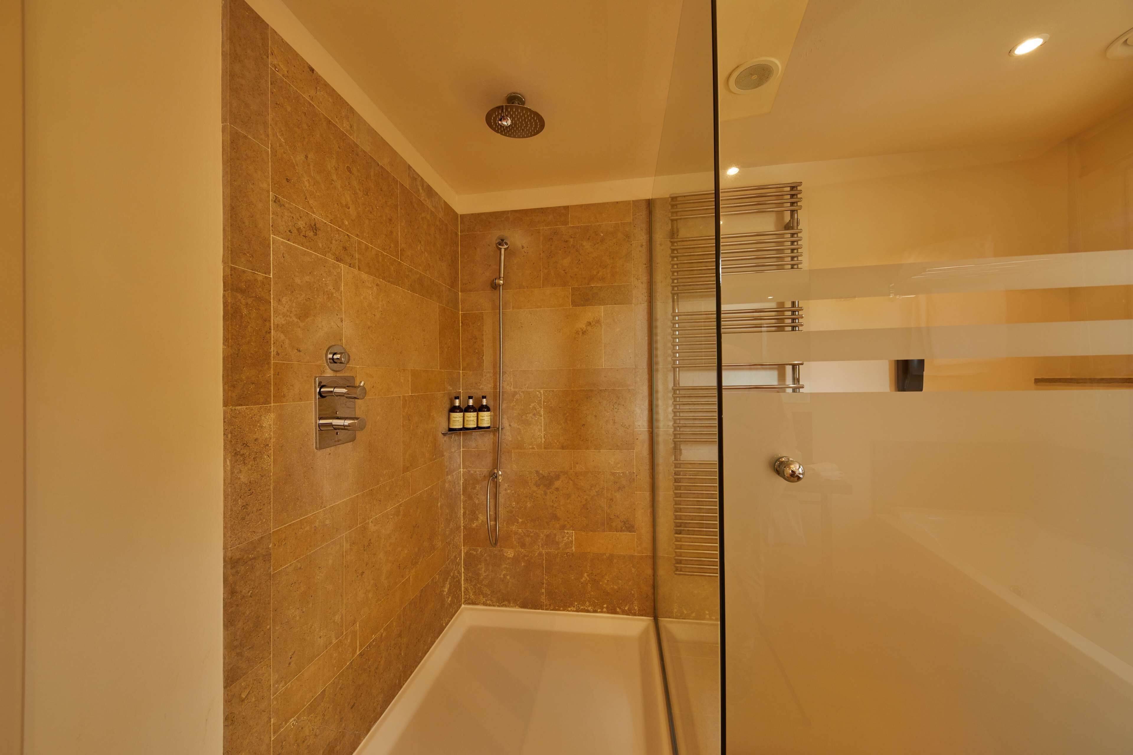 A modern bathroom with a glass shower enclosure, a bathtub, and a wall-mounted faucet.