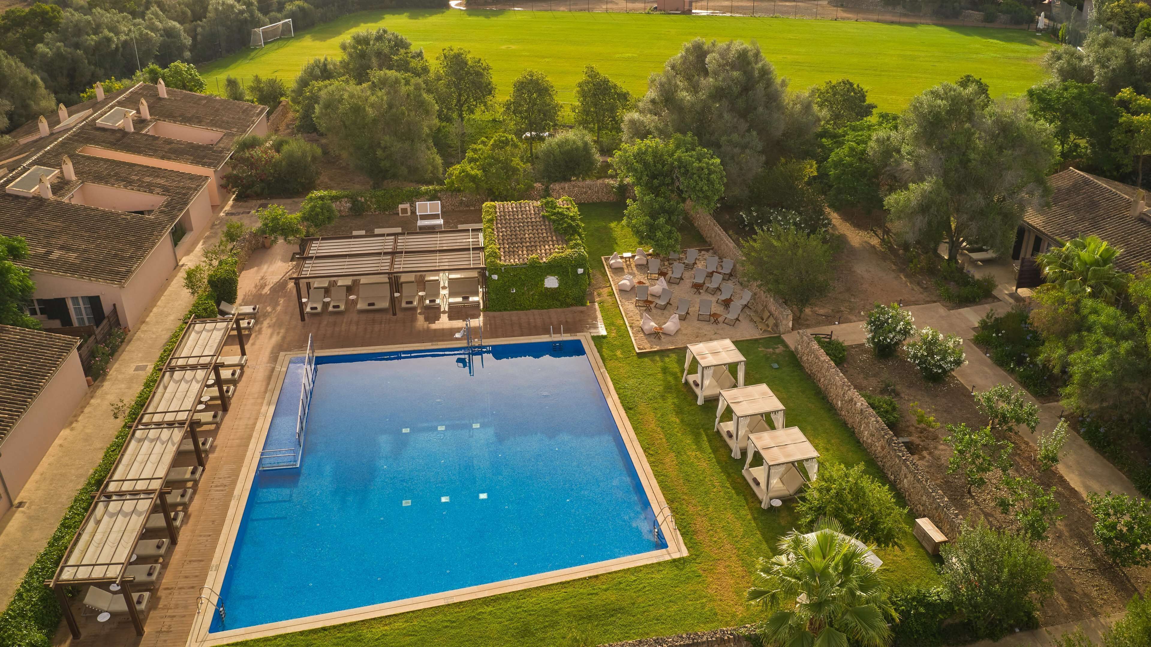 Ein großer rechteckiger Pool, umgeben von einer gepflegten Rasenfläche, mit einer Pergola und Liegestühlen in der Nähe.