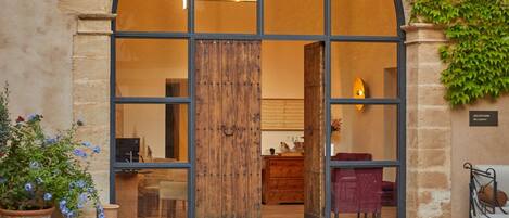 An arched entrance with a wooden door, a stone wall, and a potted plant.