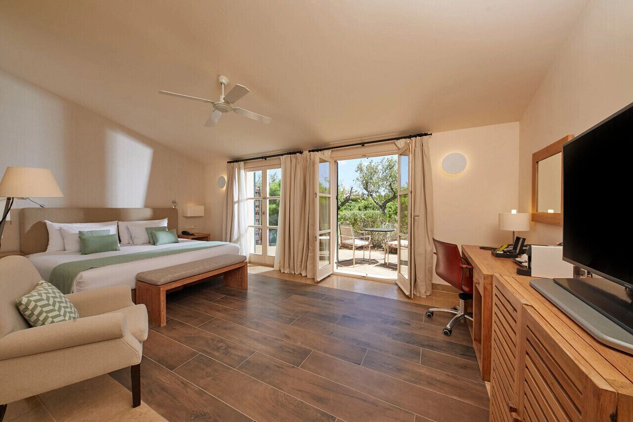 Un dormitorio con cama, escritorio, televisión y vistas al exterior.