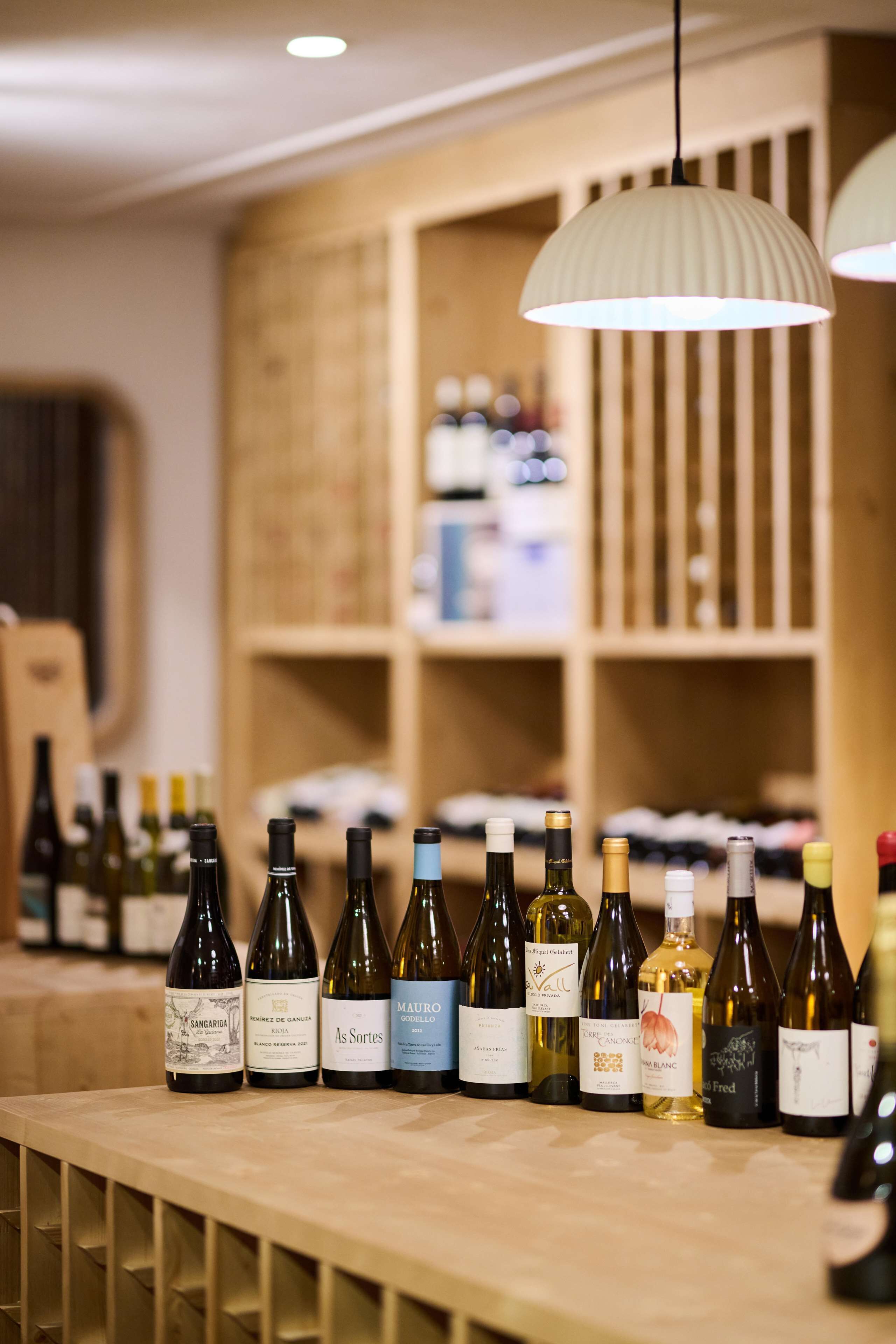 A wine tasting room with bottles of wine on a counter and wooden shelves in the background.