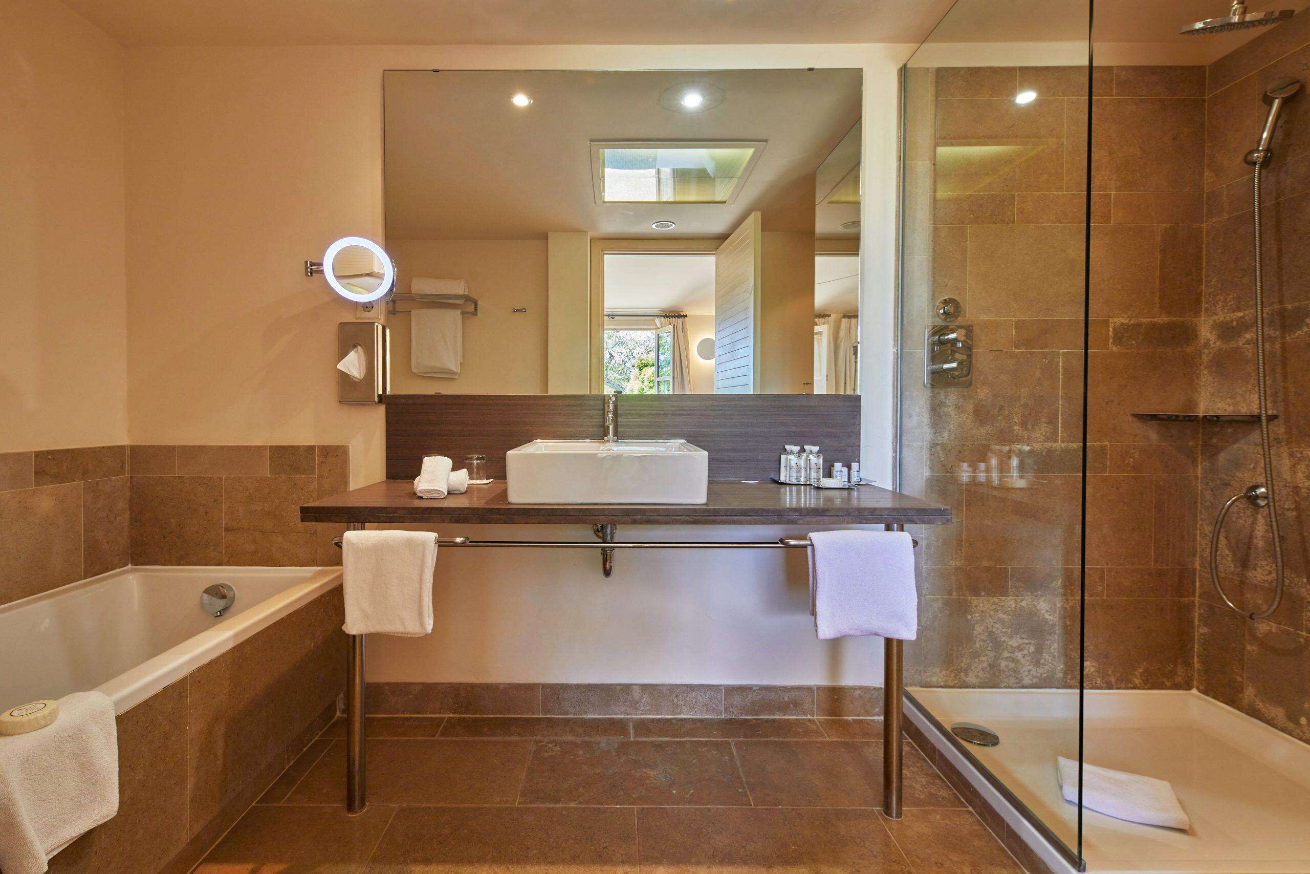 A modern bathroom with a bathtub, a glass-enclosed shower, and a vanity with a mirror.