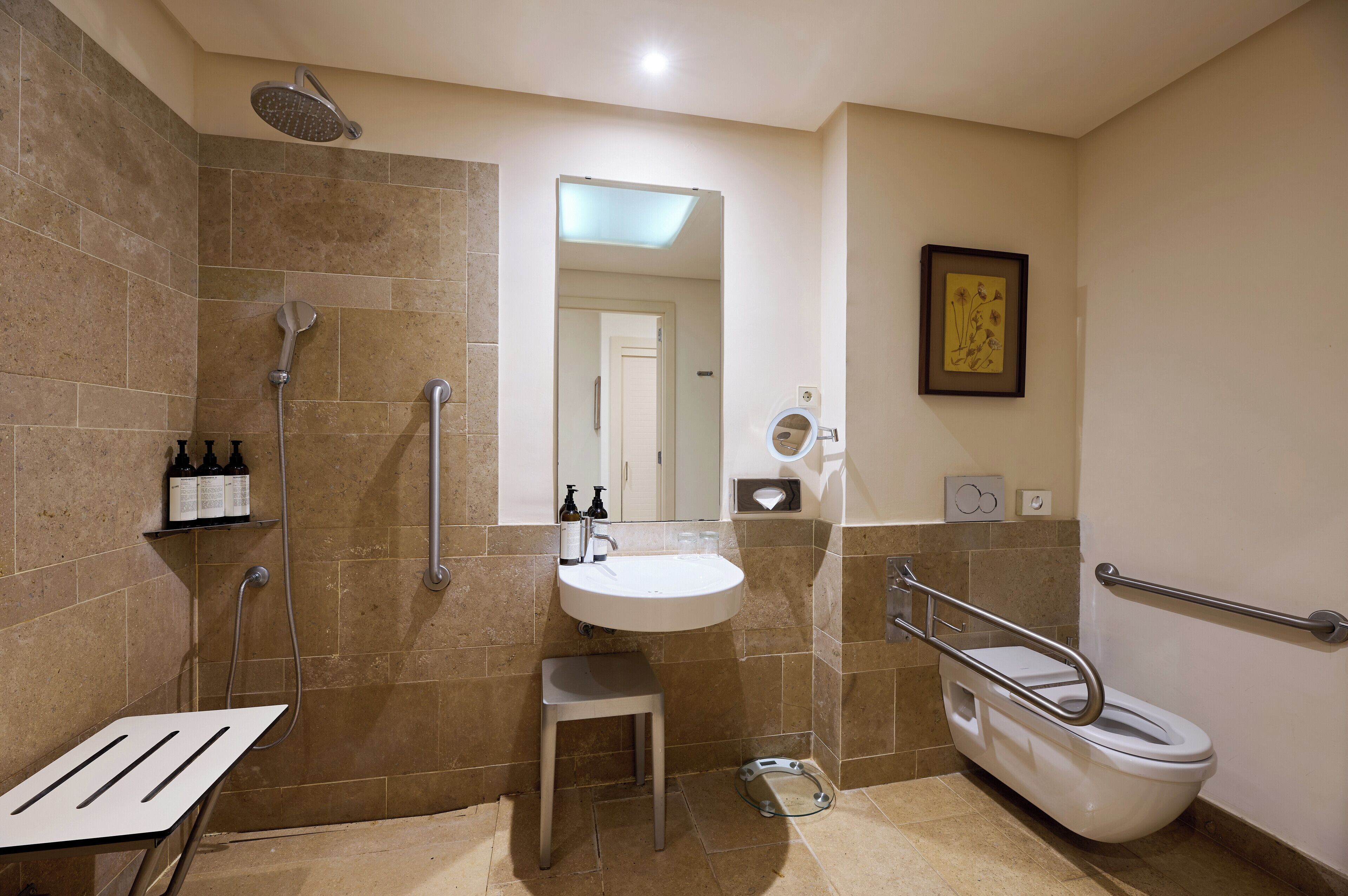 Un bagno moderno dotato di doccia, servizi igienici, lavabo e maniglie di sostegno.