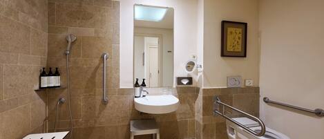 Un bagno moderno dotato di doccia, servizi igienici, lavabo e maniglie di sostegno.