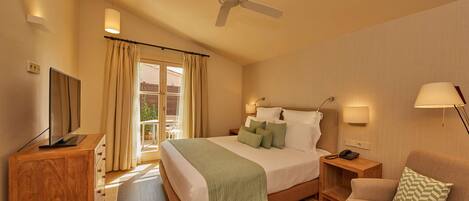 A hotel room with a bed, a TV, a desk, a chair, and a ceiling fan.