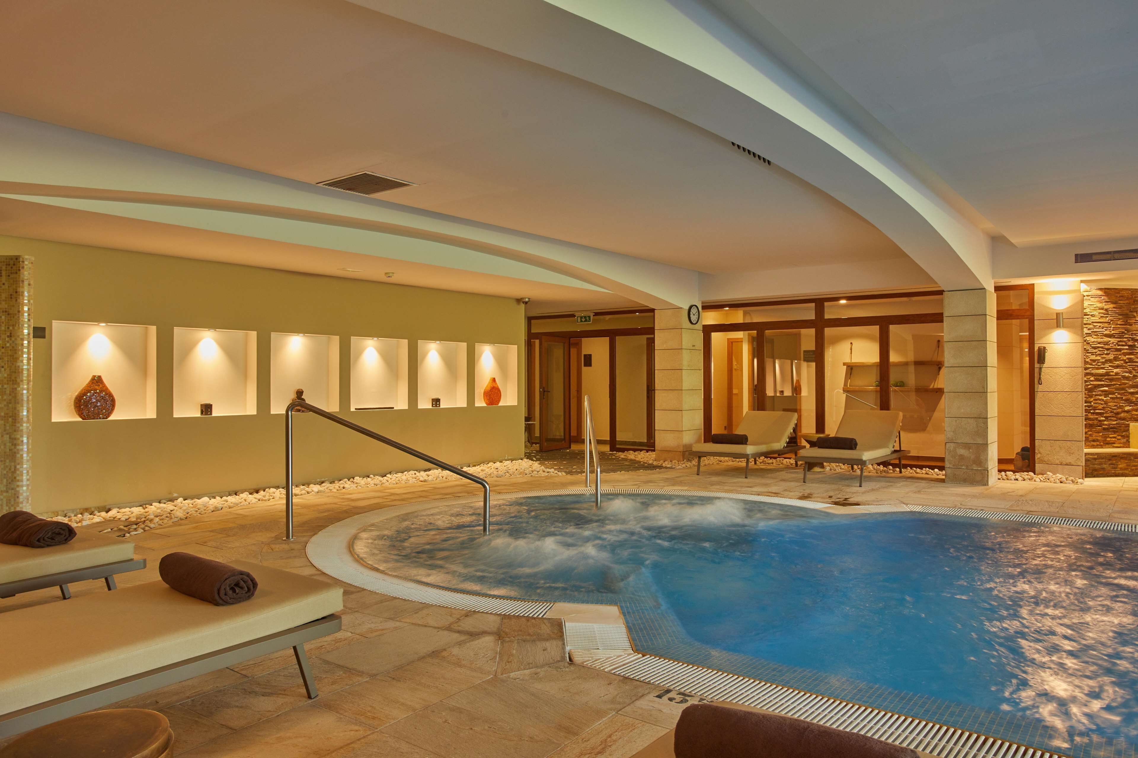 A spa area with a hot tub, seating, and a wall with lights.
