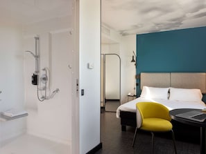 Enjoy a serene retreat with a separate shower area, comfortable bed, and cozy seating.