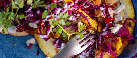 Primer plano de un plato colorido con un tenedor, con verduras vibrantes y salsa cremosa.