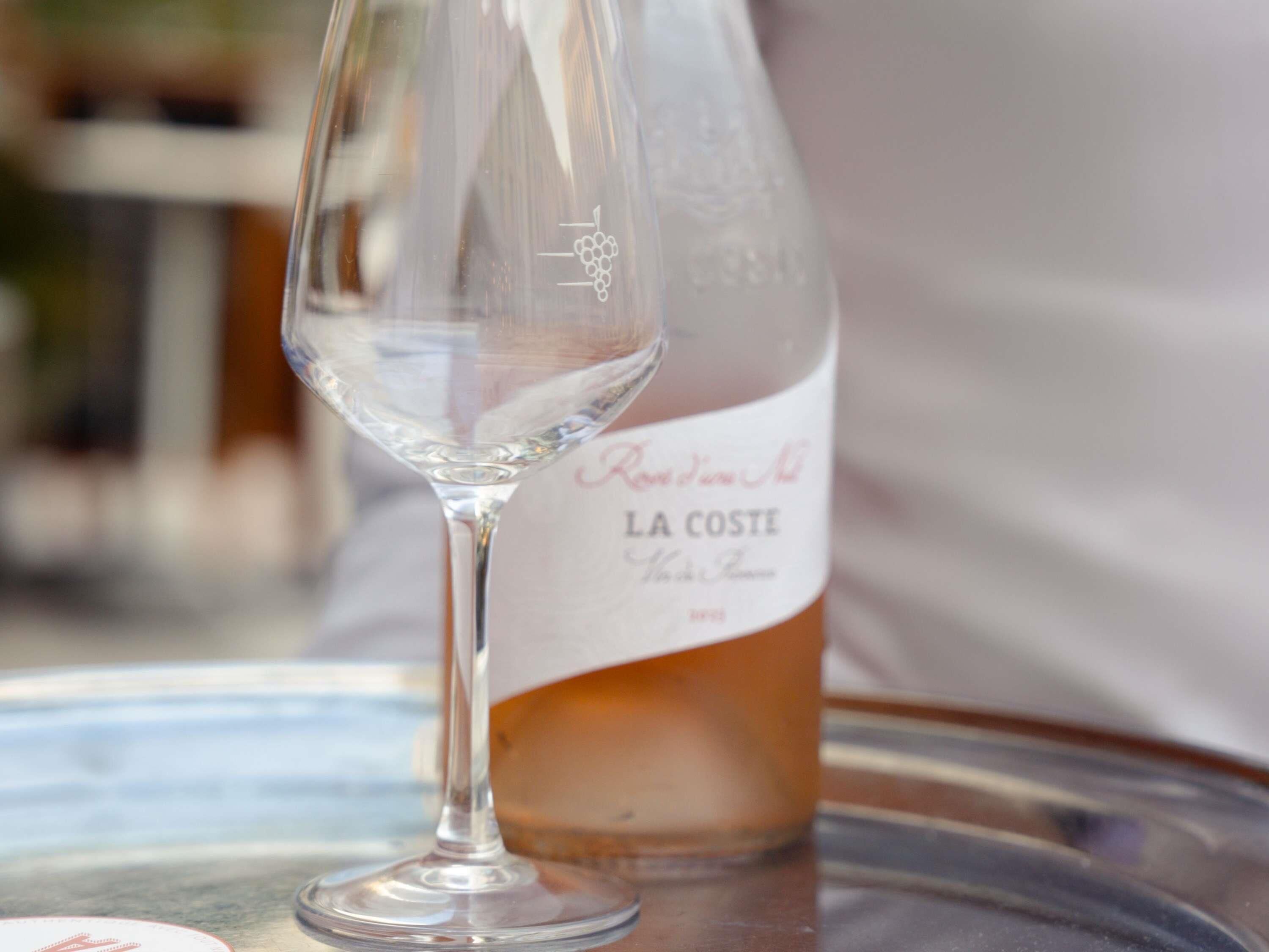 Una copa de vino y una botella sobre una superficie reflectante.