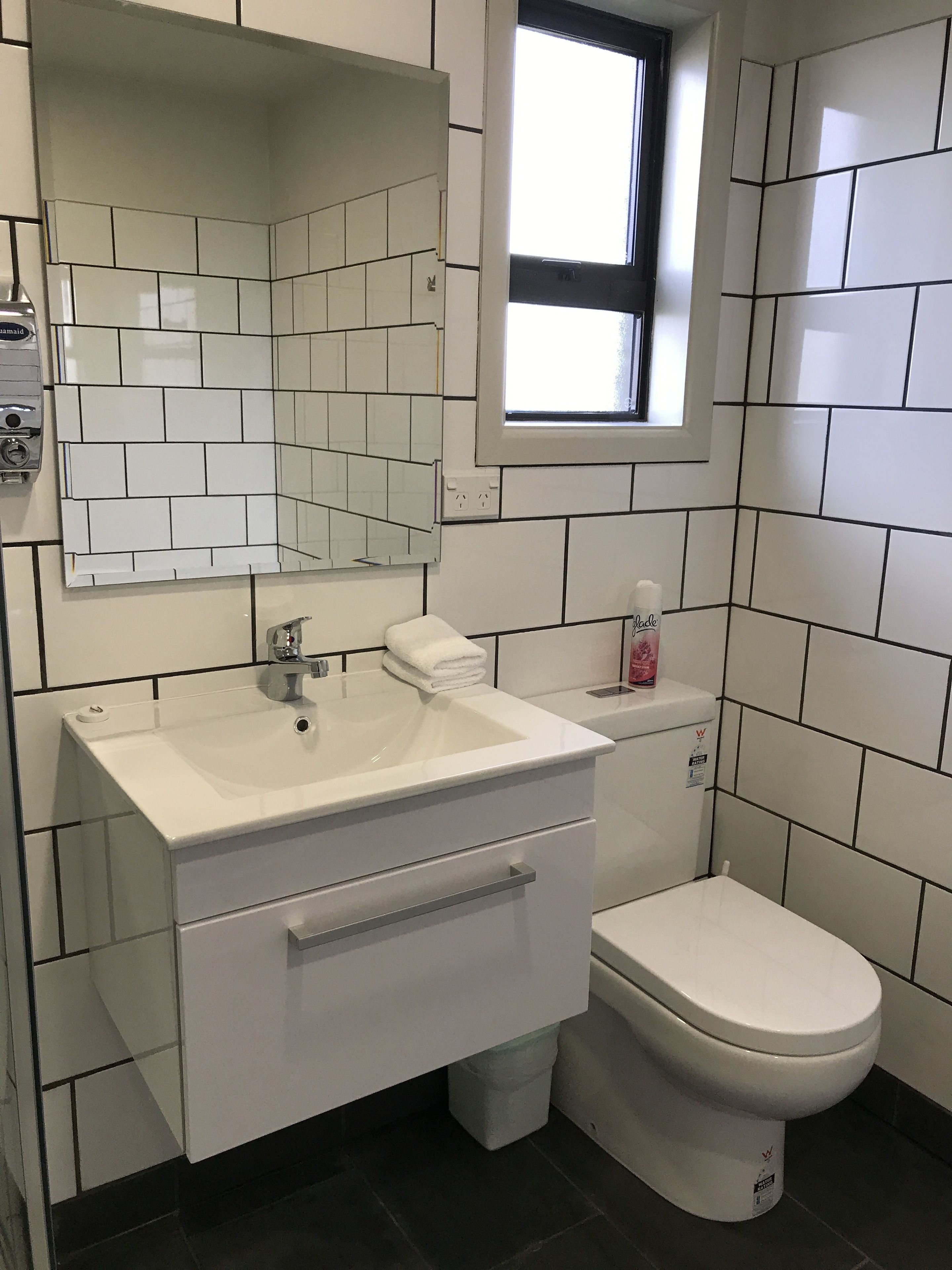 A bathroom with a white sink, a mirror, a toilet, and a window.