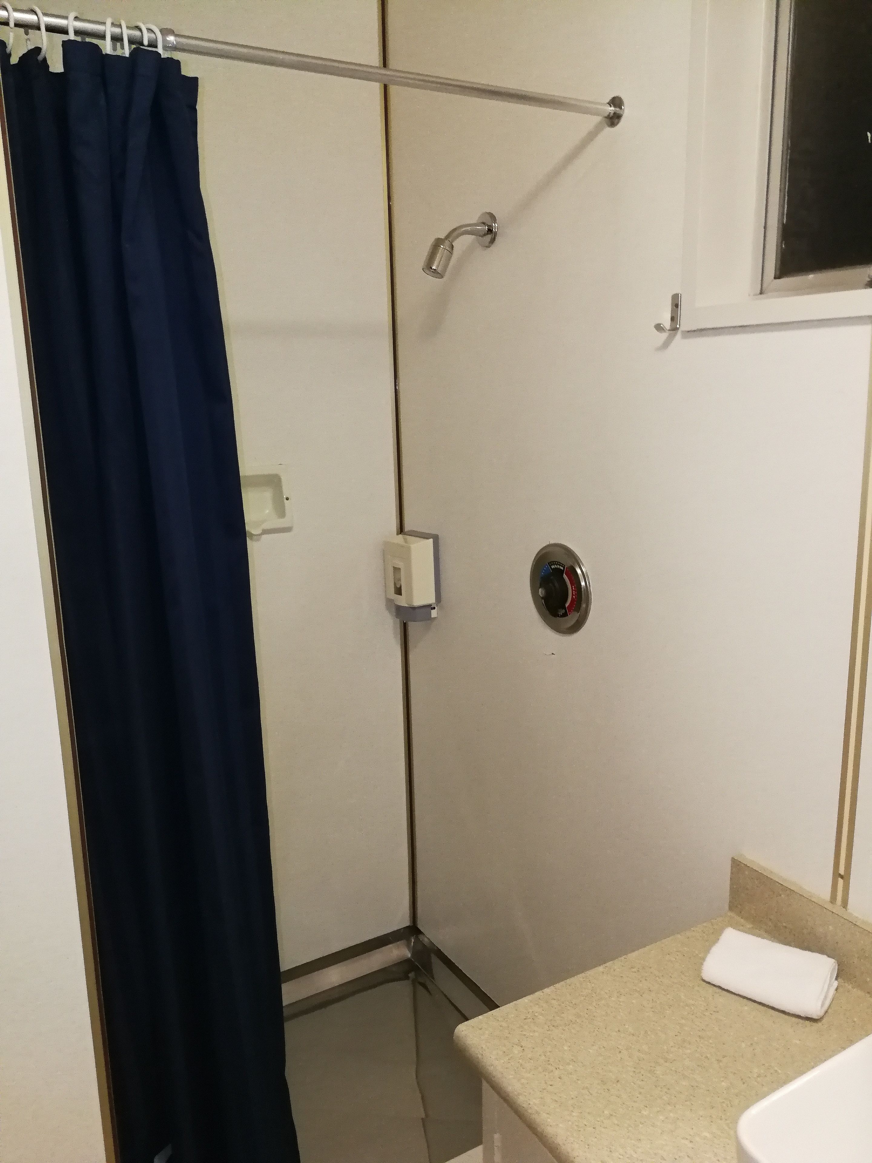 Ein Badezimmer mit Duschvorhang, Handtuch auf der Ablage und sichtbaren Wasserhahn.