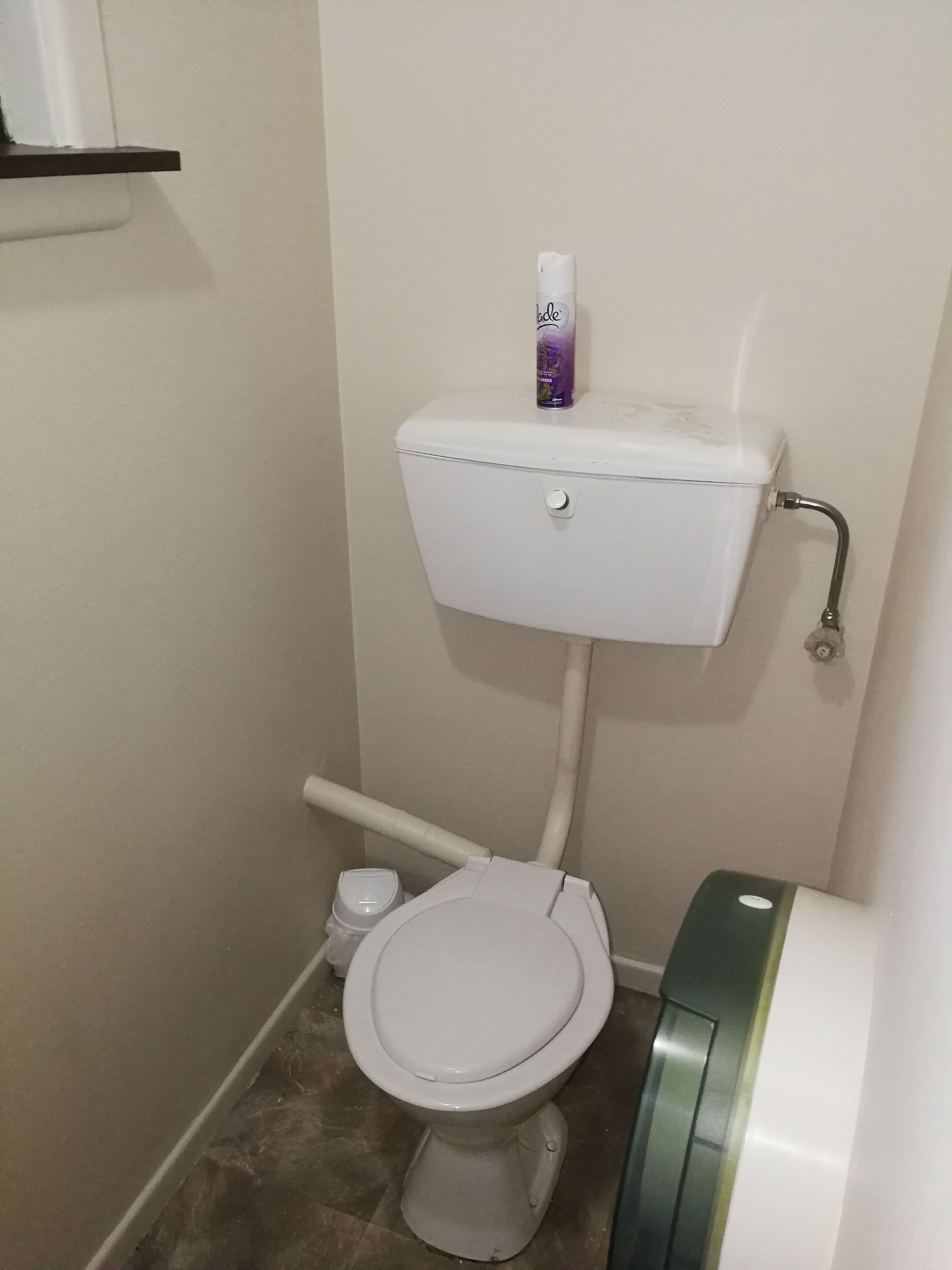 Une petite salle de bain aux dimensions réduites, avec des toilettes blanches, un lavabo blanc et un porte-rouleau de papier toilette.