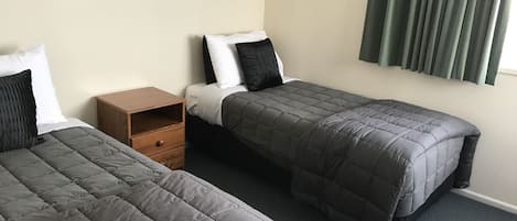 Una habitación con dos camas individuales, una mesita de noche de madera y dos lámparas de pared.