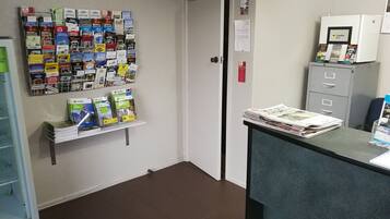 A reception area with a bulletin board displaying various travel guides, a counter with newspapers, and a filing cabinet.