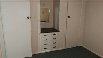 Una habitación pequeña y cerrada con una puerta blanca, un espejo y una encimera negra con cajones.
