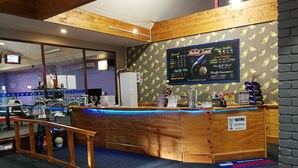 A billiards hall with a wooden counter, a digital scoreboard, and a glass display case. - Ascot Oamaru Motel (Oamaru)
