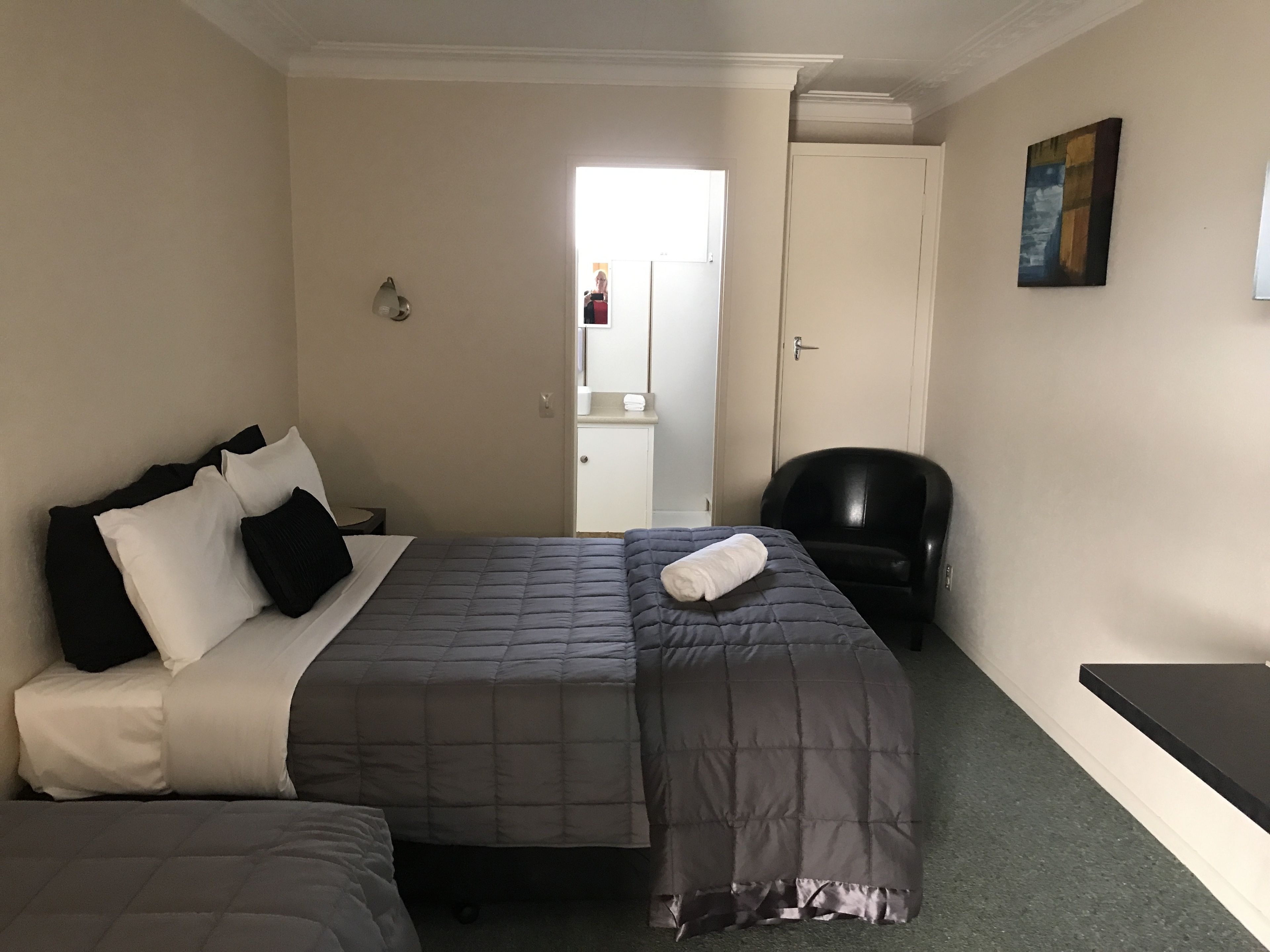 Une chambre d’hôtel comprenant un lit, une chaise, un bureau et une porte donnant accès à une salle de bain.