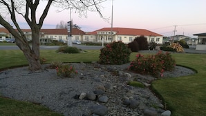 A landscaped garden with a gravel path, rocks, and flowering bushes. - Ascot Oamaru Motel (Oamaru)