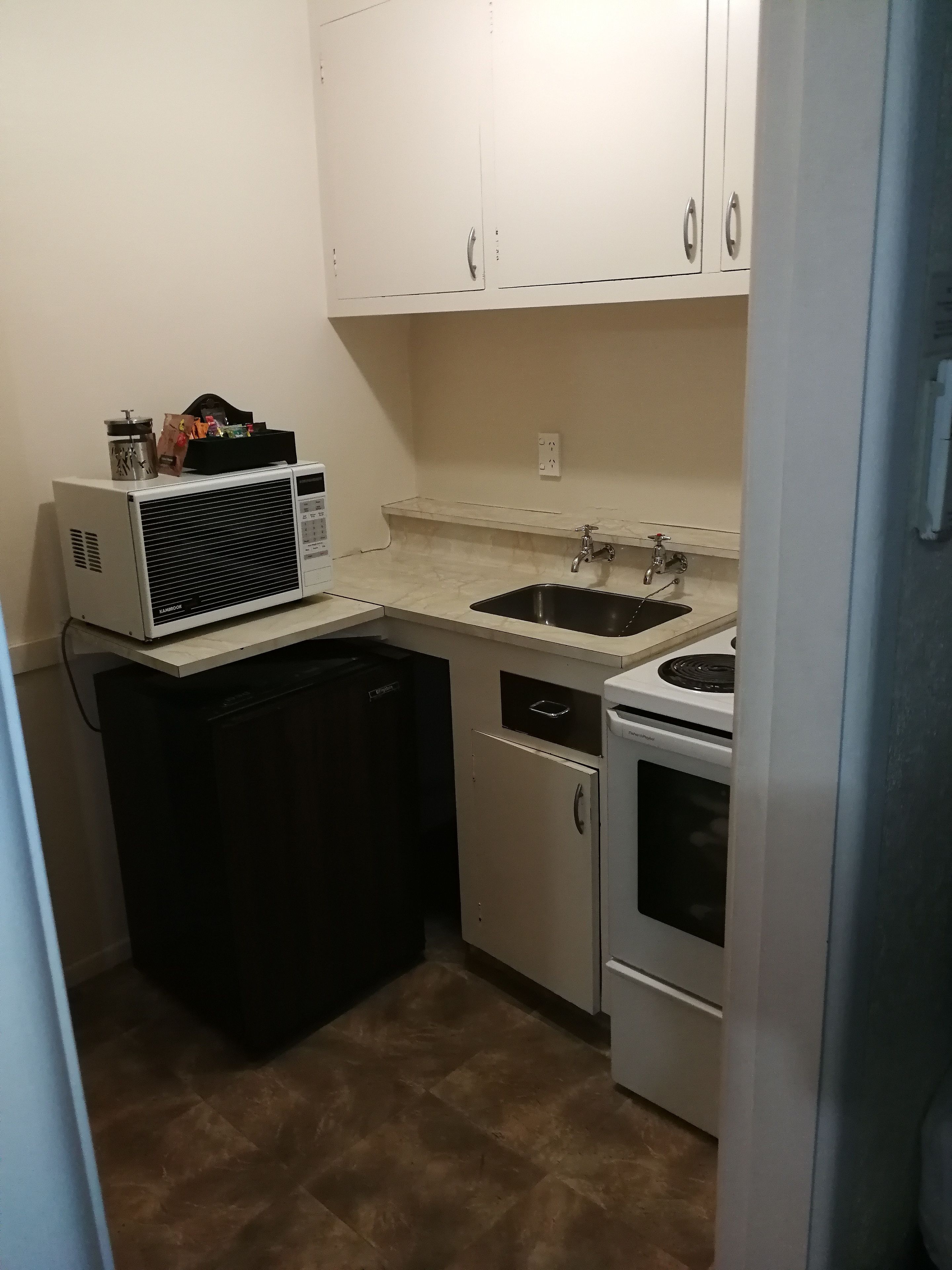 A compact kitchen with a microwave, sink, dishwasher, and stove.