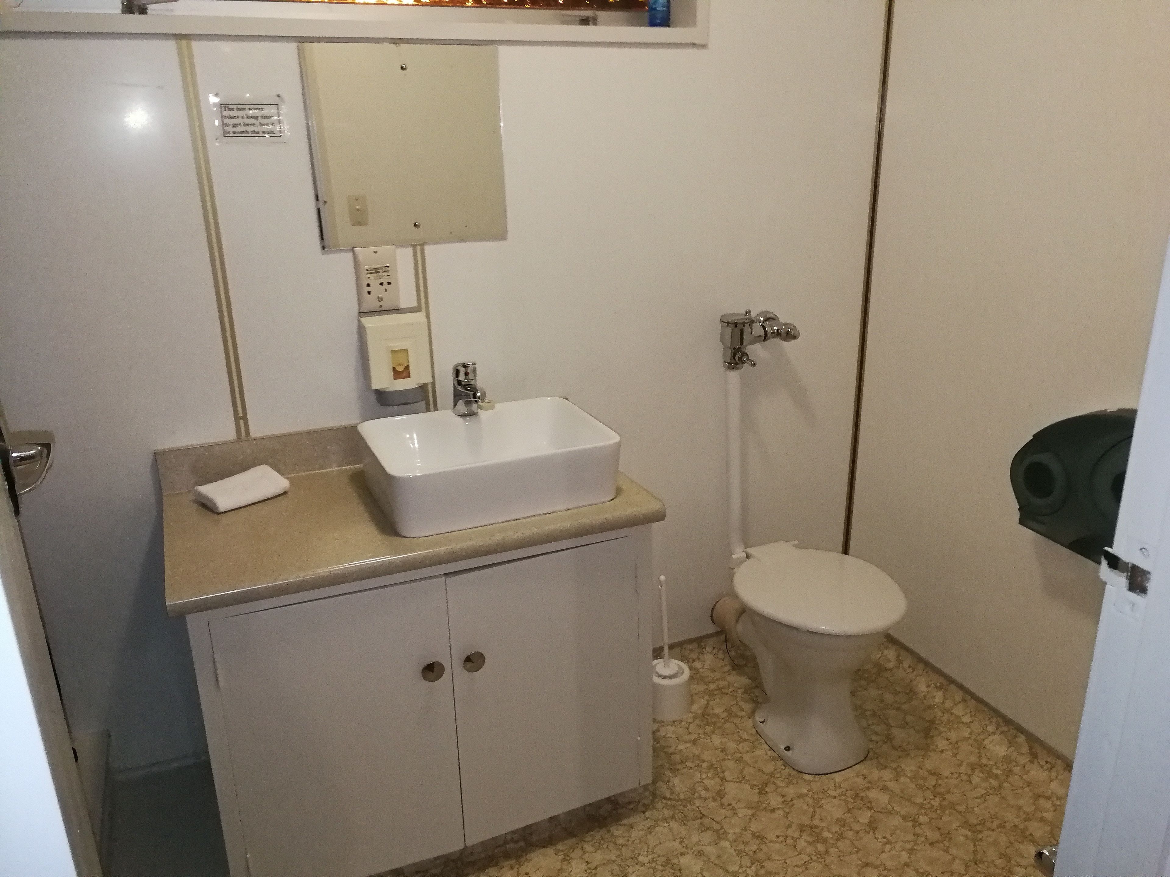 Un baño con un lavamanos blanco, un inodoro y un armario.