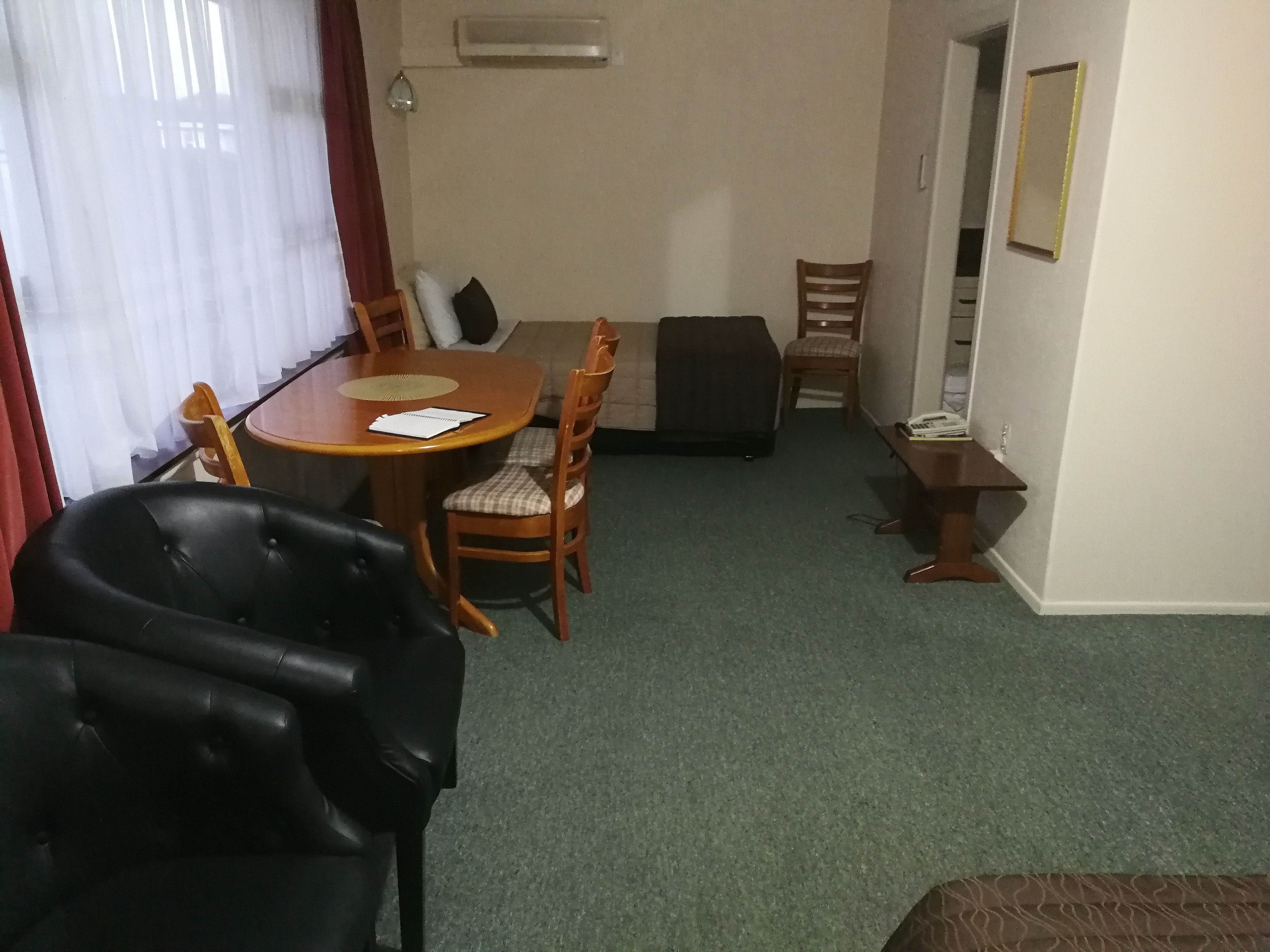 Une pièce comprenant une table à manger, deux chaises, un canapé, une petite table en bois et un téléphone.