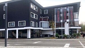 A modern building with a black and white facade, multiple windows, and a sign reading "Dormer".