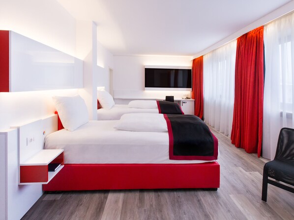 A modern hotel room with a large bed, a desk, and a TV.