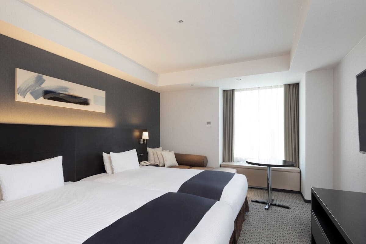 Une chambre d’hôtel avec un grand lit, un bureau, une chaise et un téléviseur.
