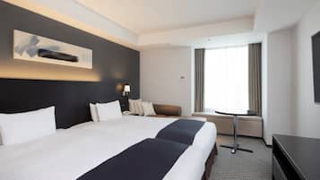 Ein Hotelzimmer mit einem großen Bett, einem Schreibtisch, einem Sessel und einem Fernseher.
