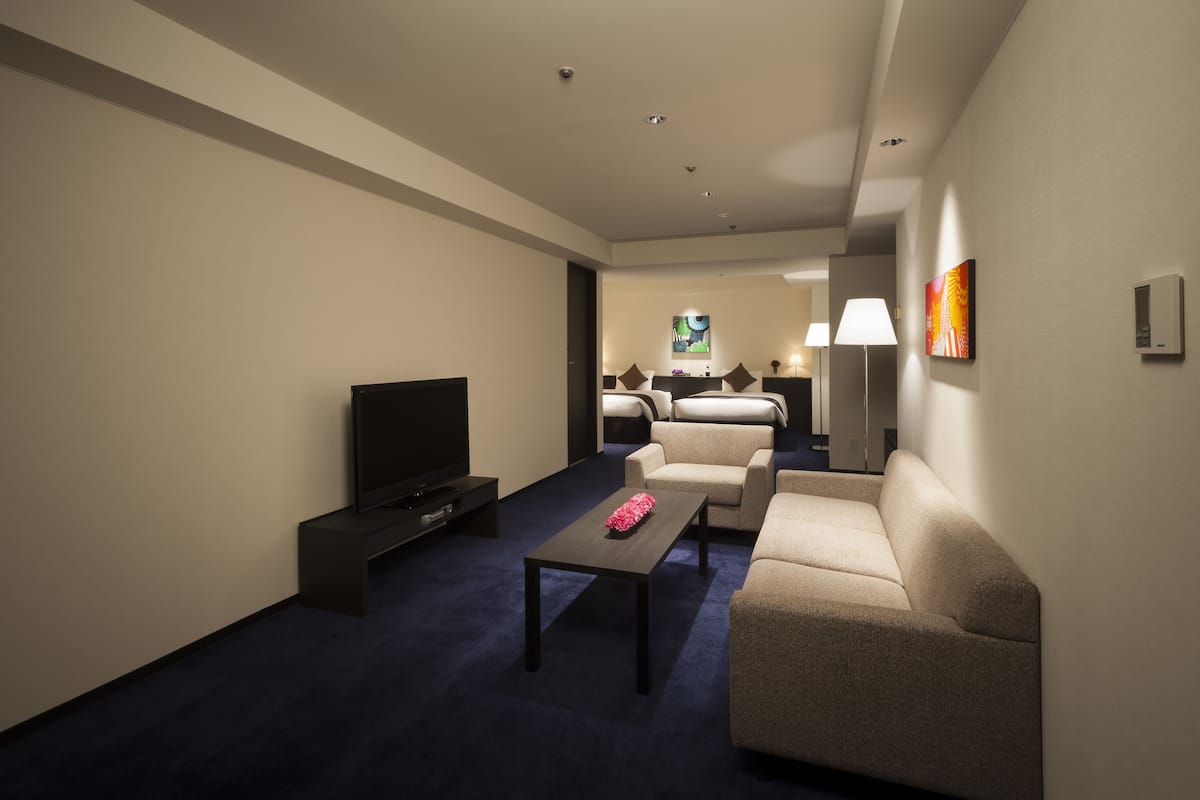 Une chambre d’hôtel équipée d’une télévision, d’un canapé, d’une table basse et d’un lit avec une table de chevet.