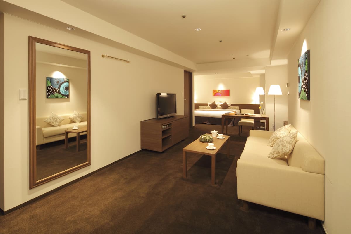 Une chambre d’hôtel moderne équipée d’un canapé, d’une table basse, d’une télévision, d’un bureau et d’un lit.