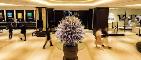 En moderne lobby med en central blomsterdekoration, en receptionsdisk og et siddeområde.