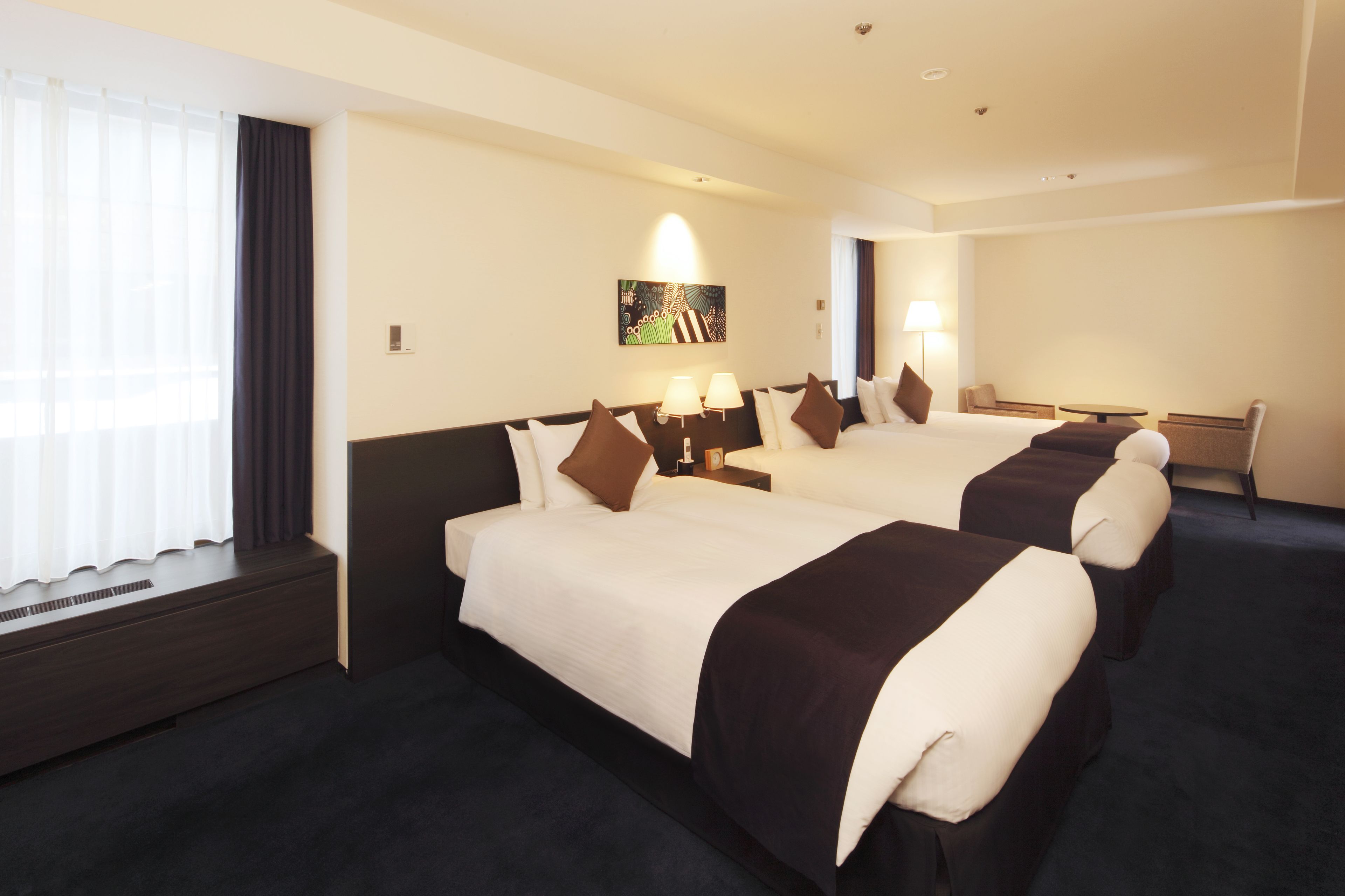 A hotel room with two beds, a desk, and a chair.