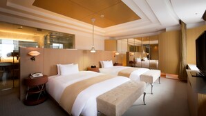 A hotel room with two beds, a sitting area, a desk, and a large mirror. - Sapporo Grand Hotel (Sapporo)
