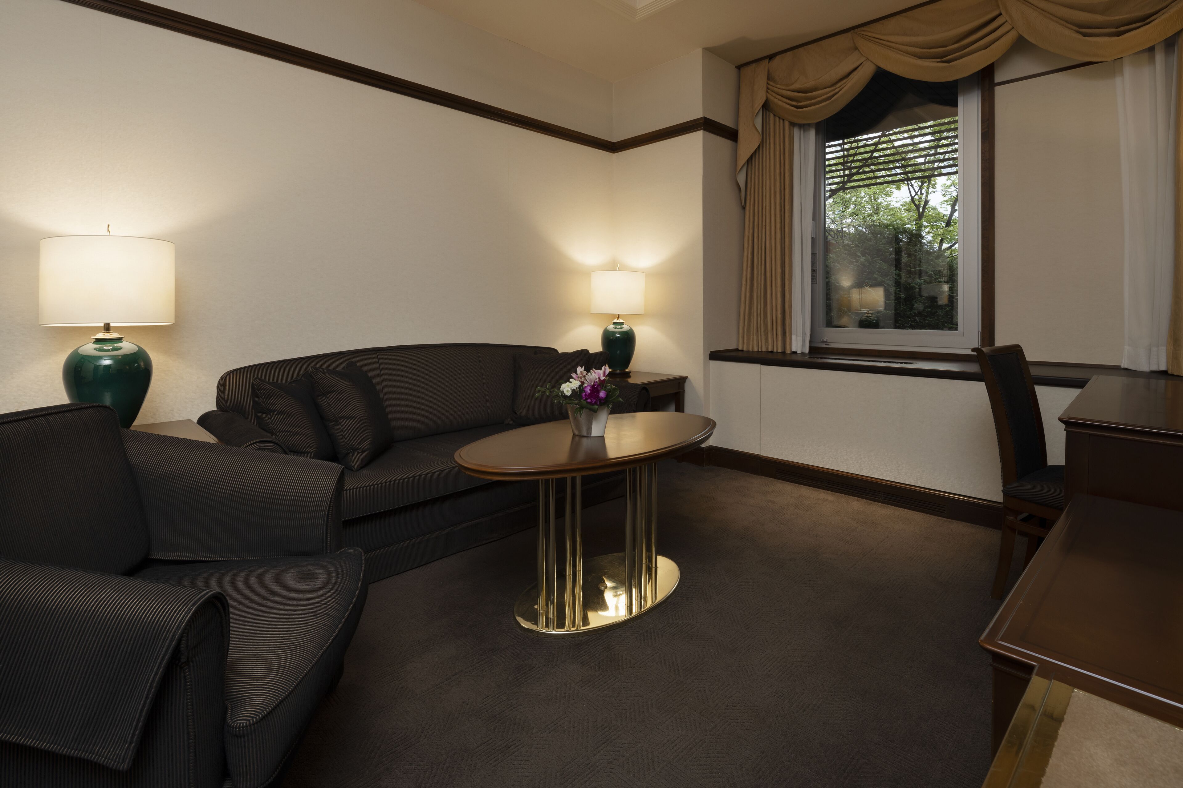 A hotel room with a sofa, a small round table, and a lamp.