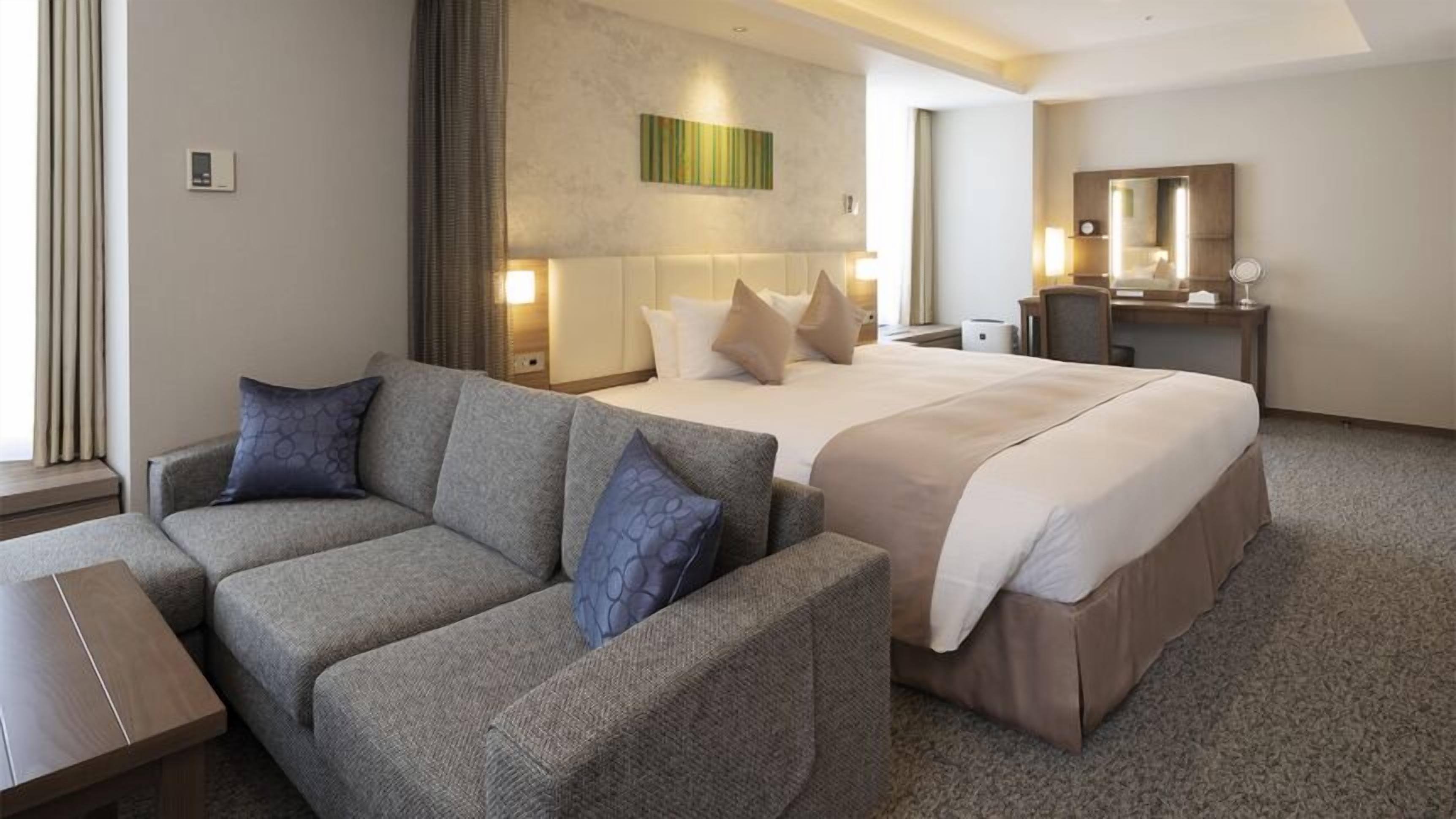Une chambre d’hôtel avec un lit, un canapé, un bureau et un miroir.