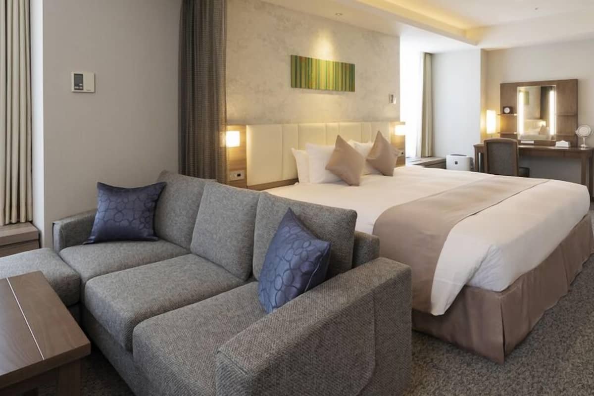 Une chambre d’hôtel avec un lit, un canapé, un bureau et un miroir.