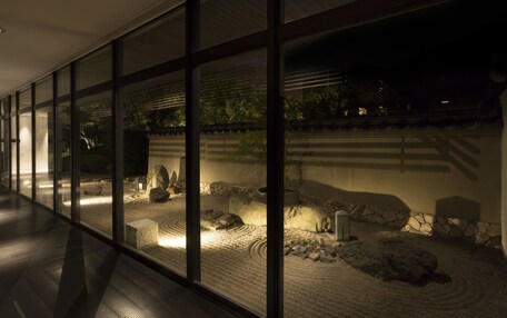 A corridor with large windows overlooking a landscaped garden area with rocks and a stone wall.