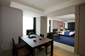 A hotel room with a dining area, a bed, and a desk with a lamp. - Sapporo Grand Hotel (Sapporo)