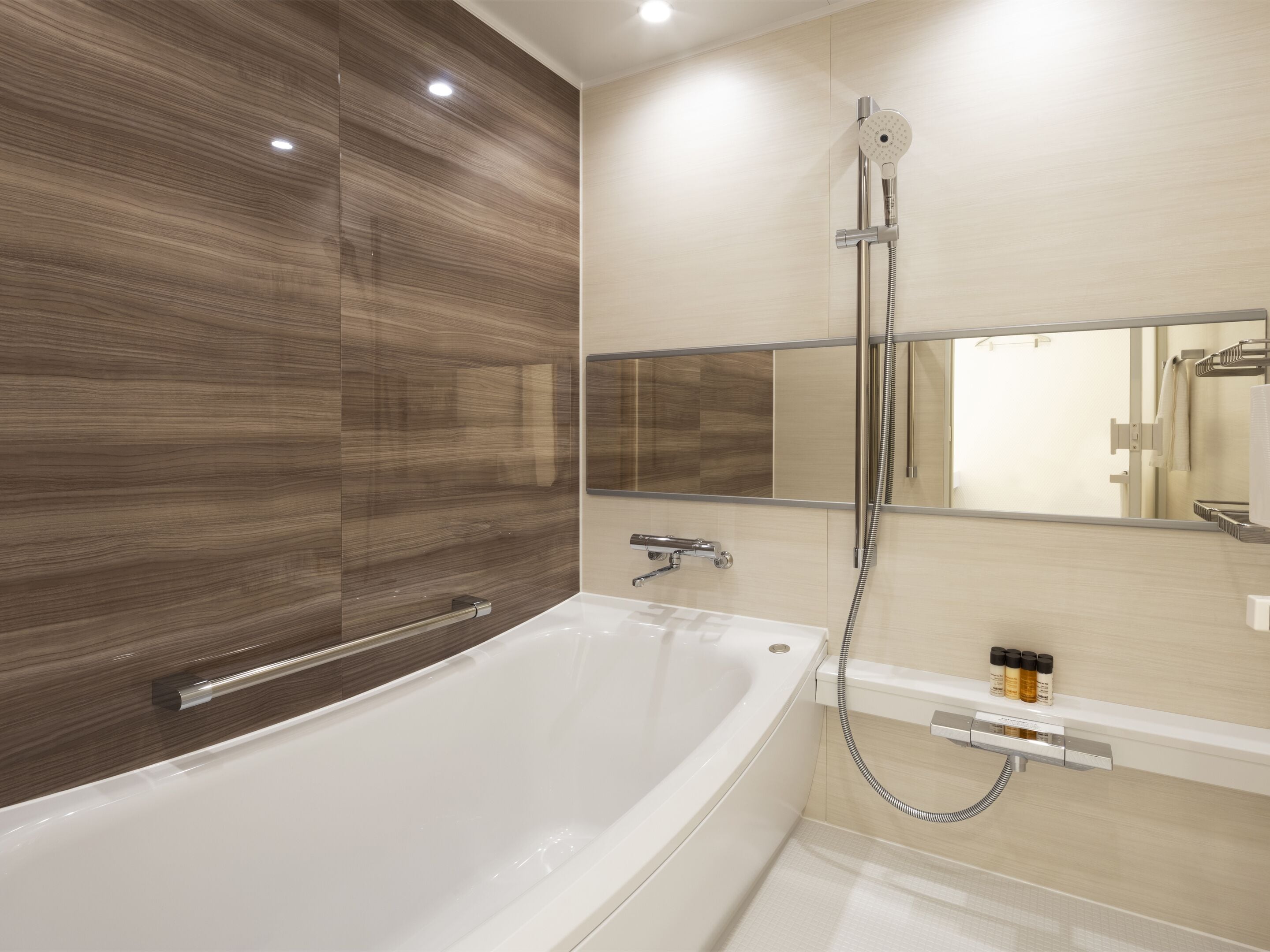 A modern bathroom with a freestanding bathtub, a wall-mounted mirror, and a showerhead.