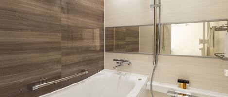 A modern bathroom with a freestanding bathtub, a wall-mounted mirror, and a showerhead.