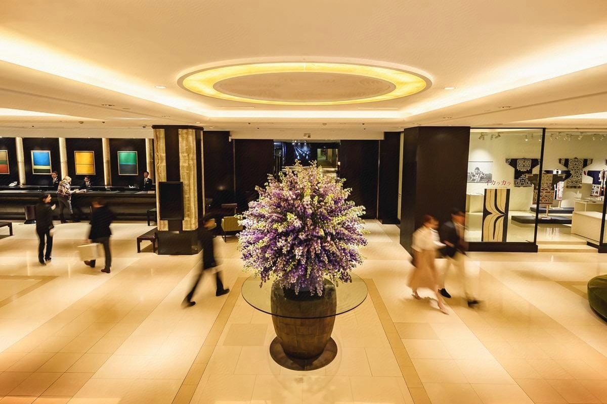 Un vestíbulo con un arreglo floral central, una recepción y un área de estar.