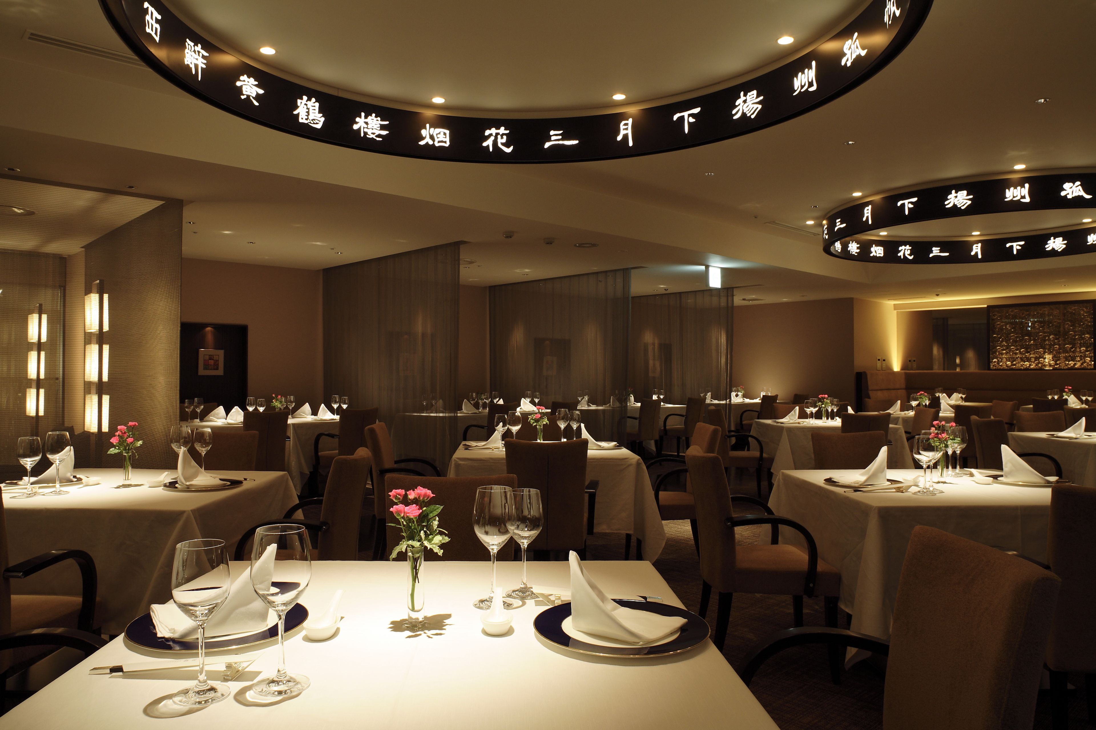 A restaurant with tables set for dining, featuring a circular sign with text above the tables.