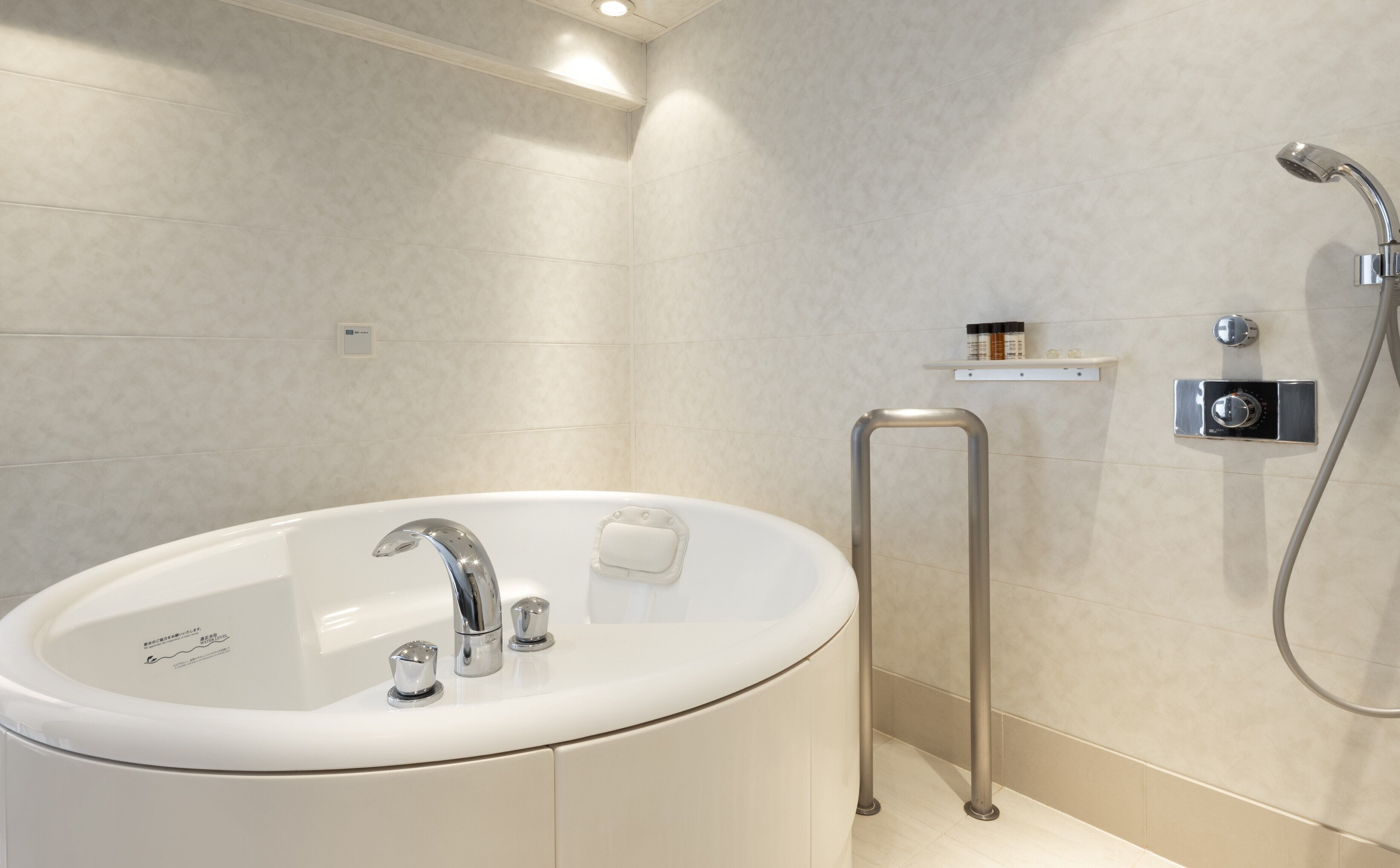 A modern bathroom with a freestanding bathtub, a handheld showerhead, and a towel rack.