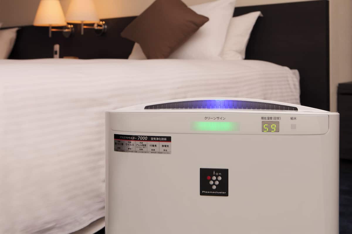 Une chambre d’hôtel équipée d’un lit, d’une table de chevet et d’un purificateur d’air fixé au mur.