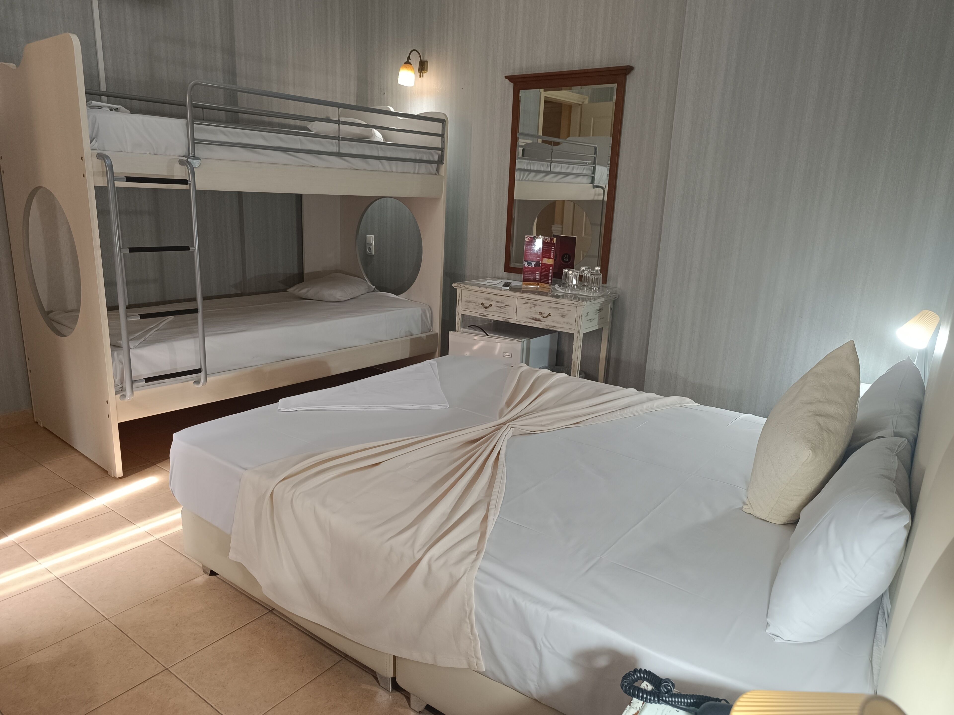 Ein Zimmer mit Etagenbett, Schreibtisch mit Spiegel und Nachttisch.
