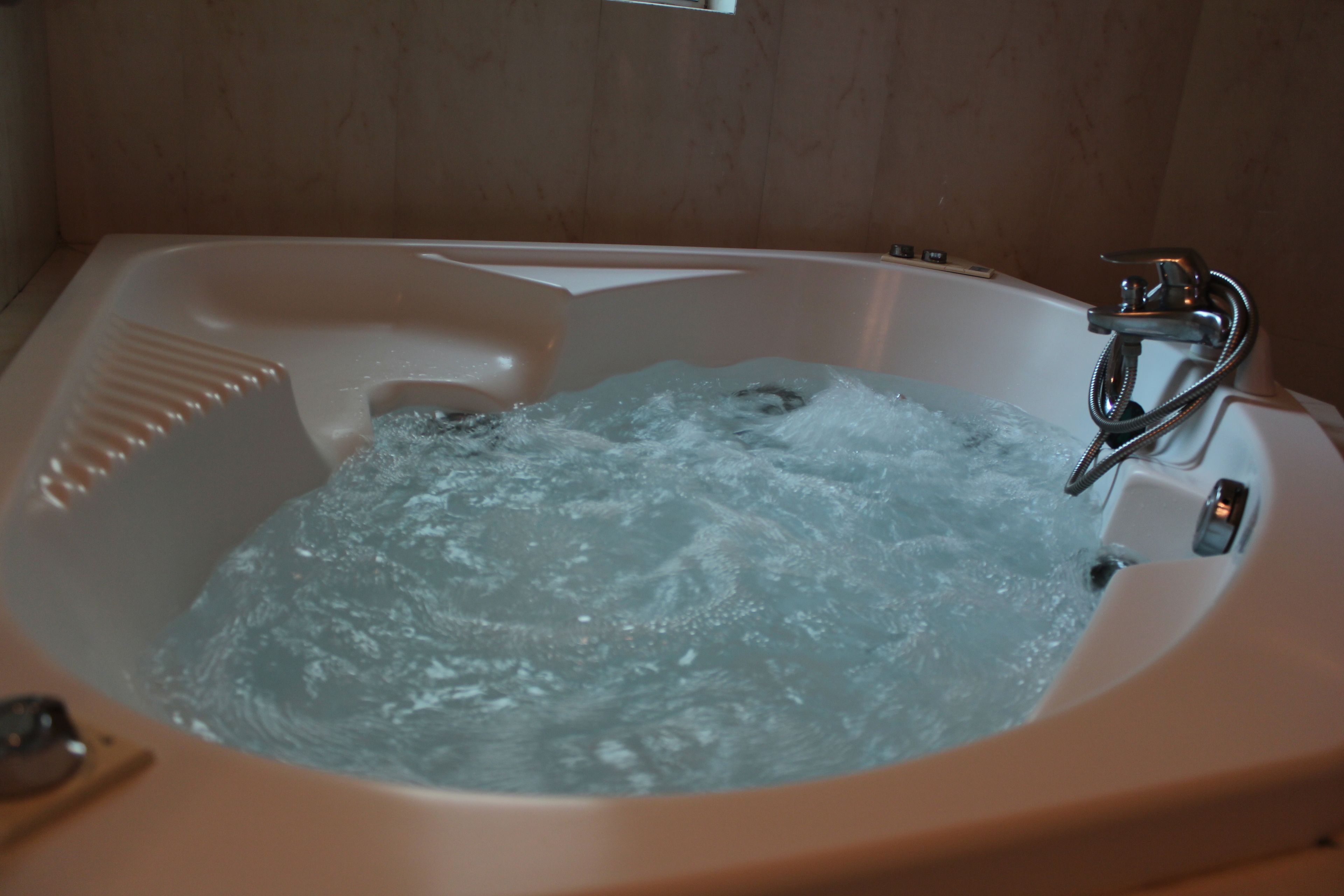 Una bañera con agua corriente, un cabezal de ducha y un panel de control.