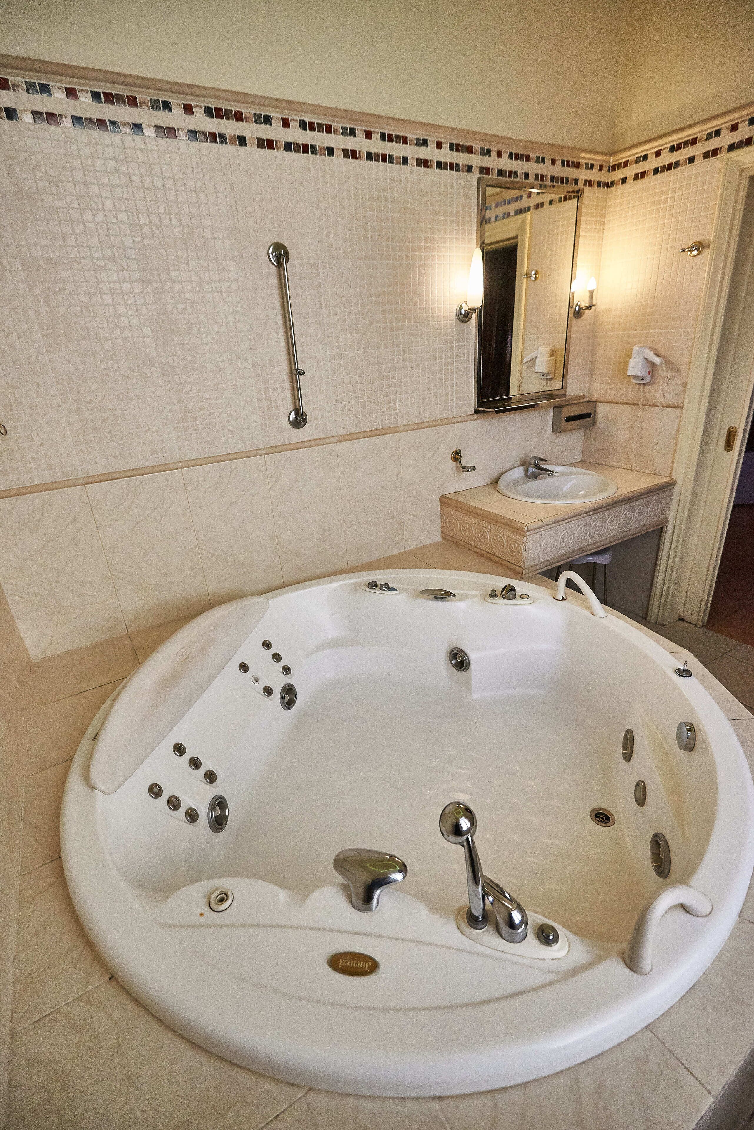 A bathroom with a large white bathtub, a sink, and a mirror.